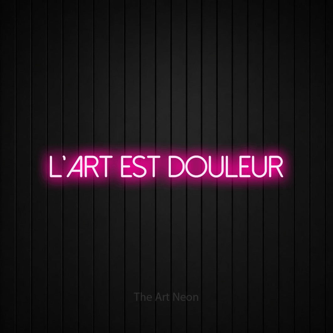 “L'art est douleur” LED neon sign in hot pink, with thin sans-serif lettering, shown against black vertical wall slats.