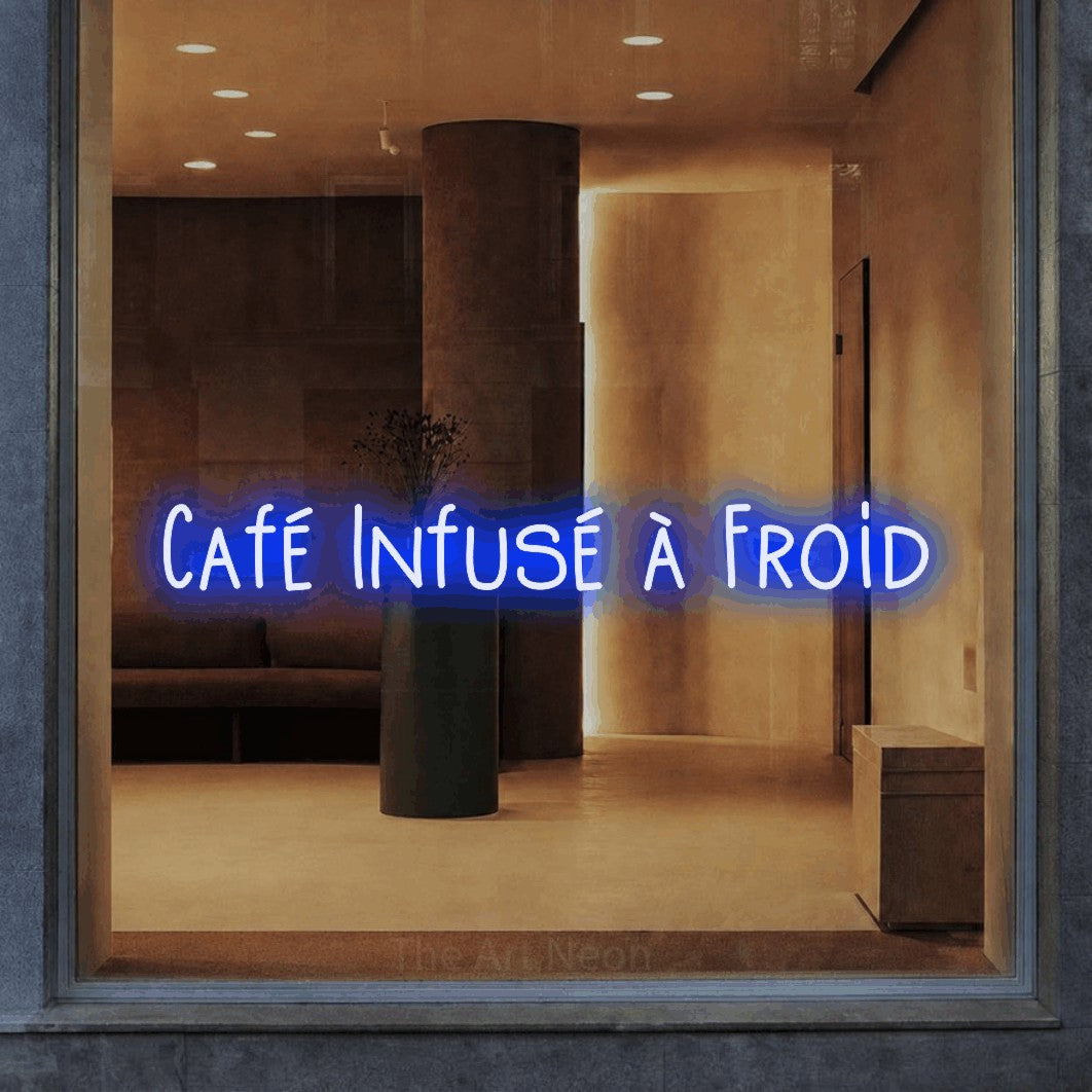 Lettrage en néon LED « Café infusé à froid » en bleu, en lettres étroites dessinées à la main, présenté dans un intérieur aux tons chauds, pour un café.