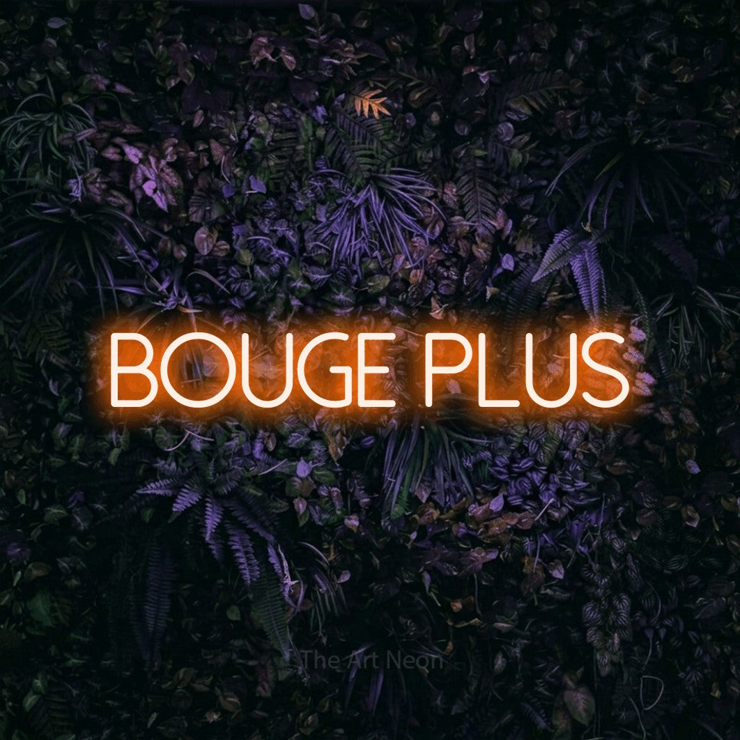 “Bouge plus” LED neon sign in orange, with thin sans-serif lettering, shown against a dark wall with purple flowers.
