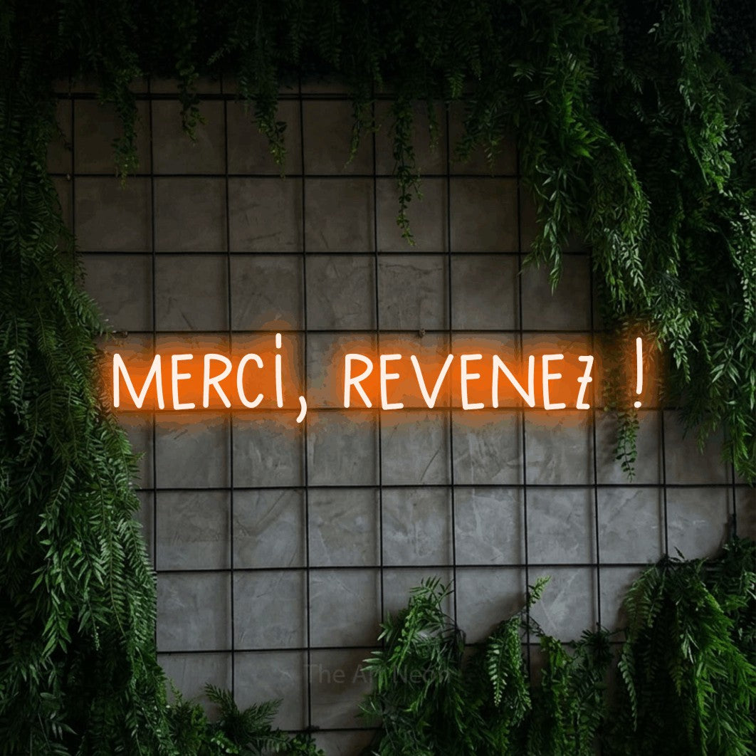 “Merci, revenez !” LED neon sign in orange, with narrow hand-drawn lettering, shown against an ivy-covered concrete grid.
