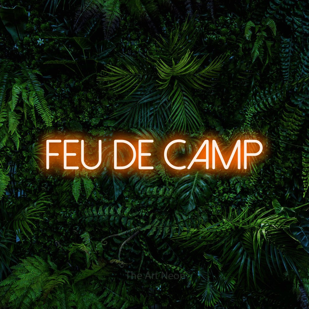 “Feu de camp” LED neon sign in orange, with thin sans-serif lettering, shown against dense tropical foliage.