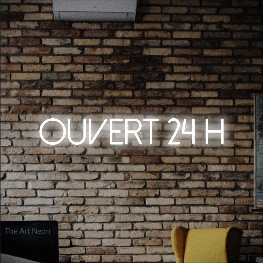 “Ouvert 24 h” LED neon sign in cool white, with thin sans-serif lettering, shown against warm-toned brickwork.