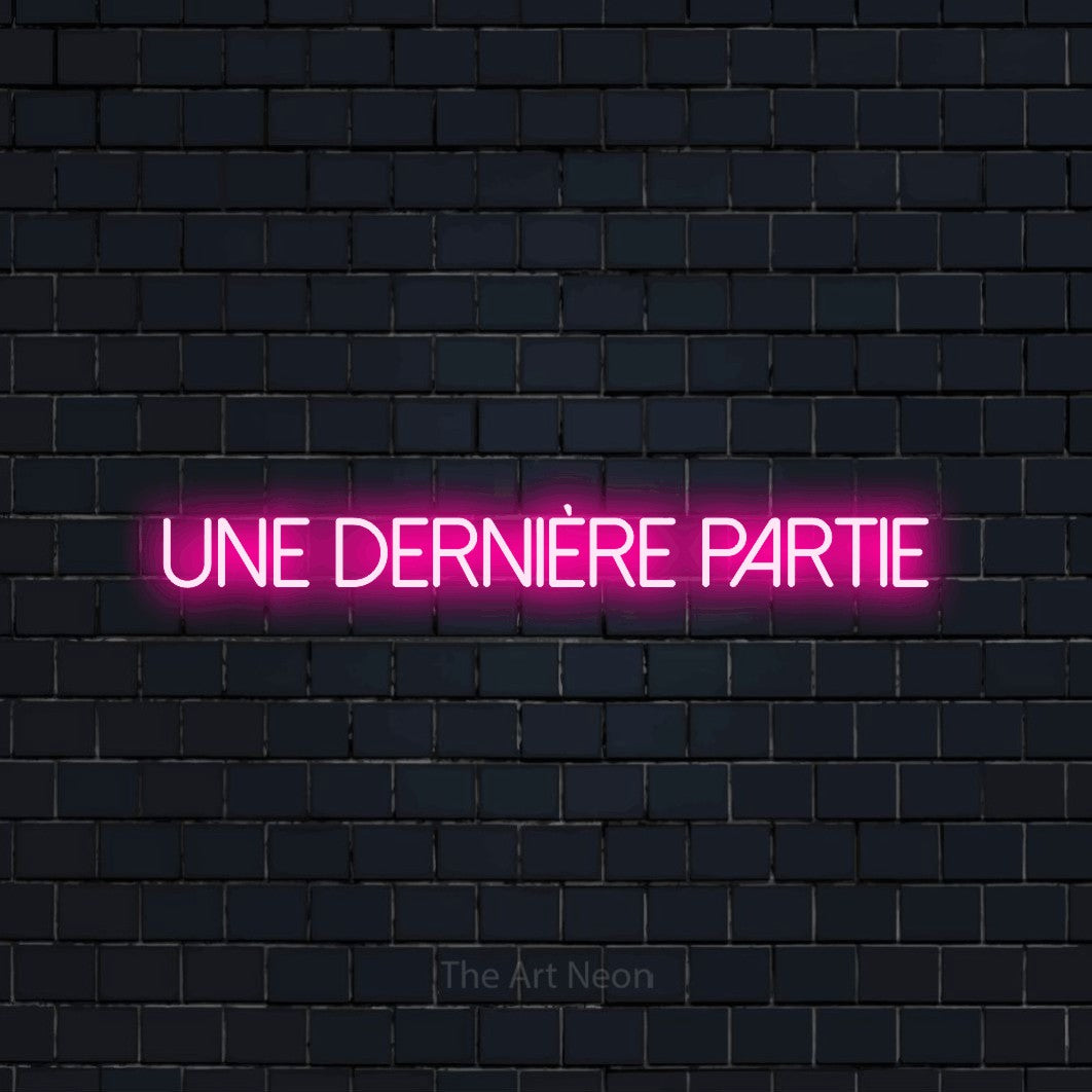 “Une dernière partie” LED neon sign in hot pink, with thin sans-serif lettering, shown against a dark navy brick wall.