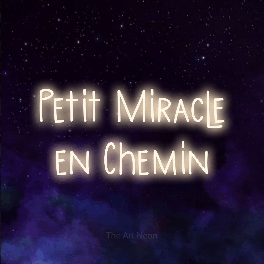 “Petit miracle en chemin” LED neon sign in warm white, with narrow hand-drawn lettering across 2 lines, shown against a purple galaxy backdrop.