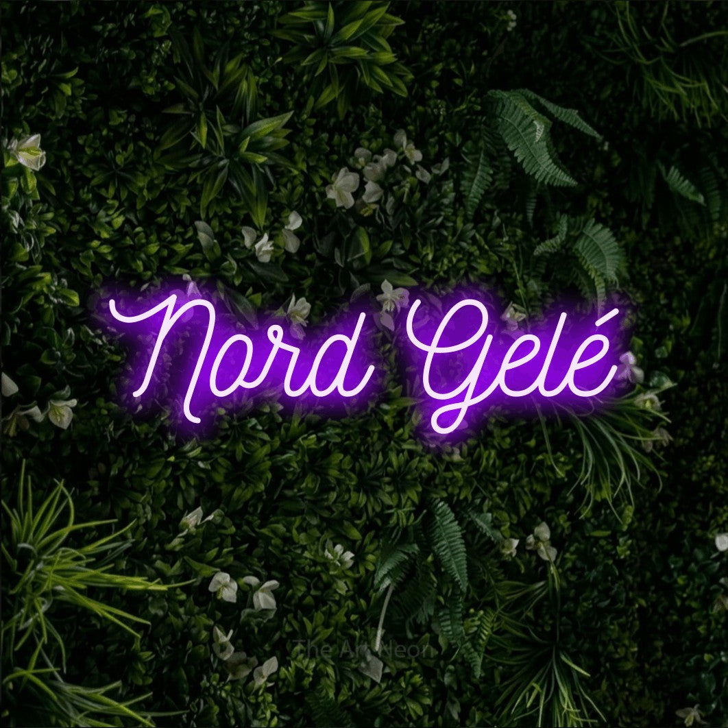 “Nord gelé” LED neon sign in purple, with ornate cursive lettering, shown against a dense green plant wall.