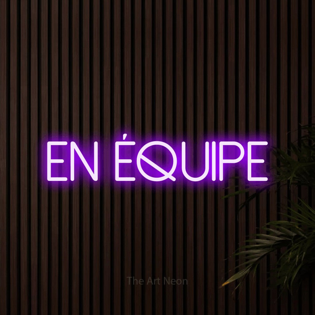 “En équipe” LED neon sign in purple, with thin sans-serif lettering, shown against dark wooden wall slats.