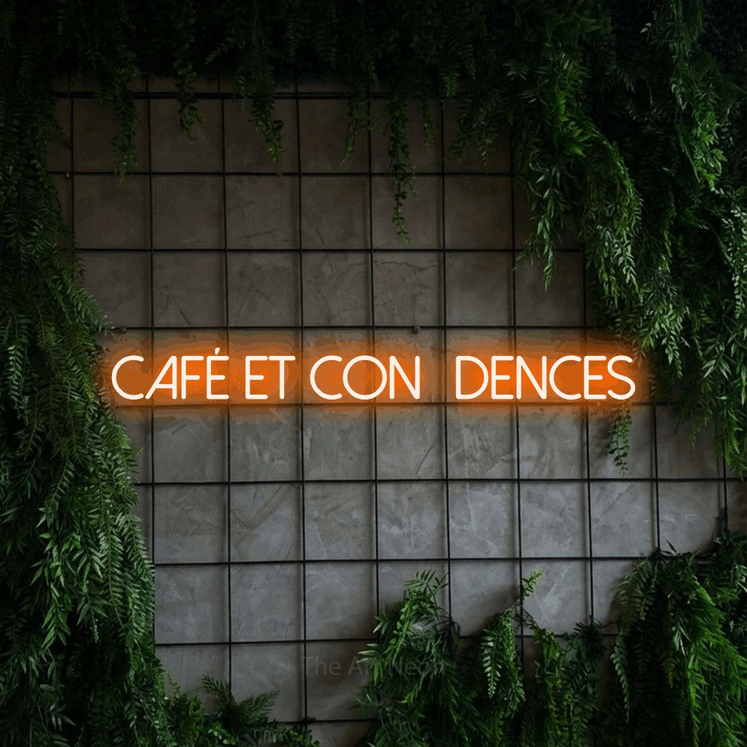 “Café et confidences” LED neon sign in orange, with thin sans-serif lettering, shown against an ivy-covered concrete grid.