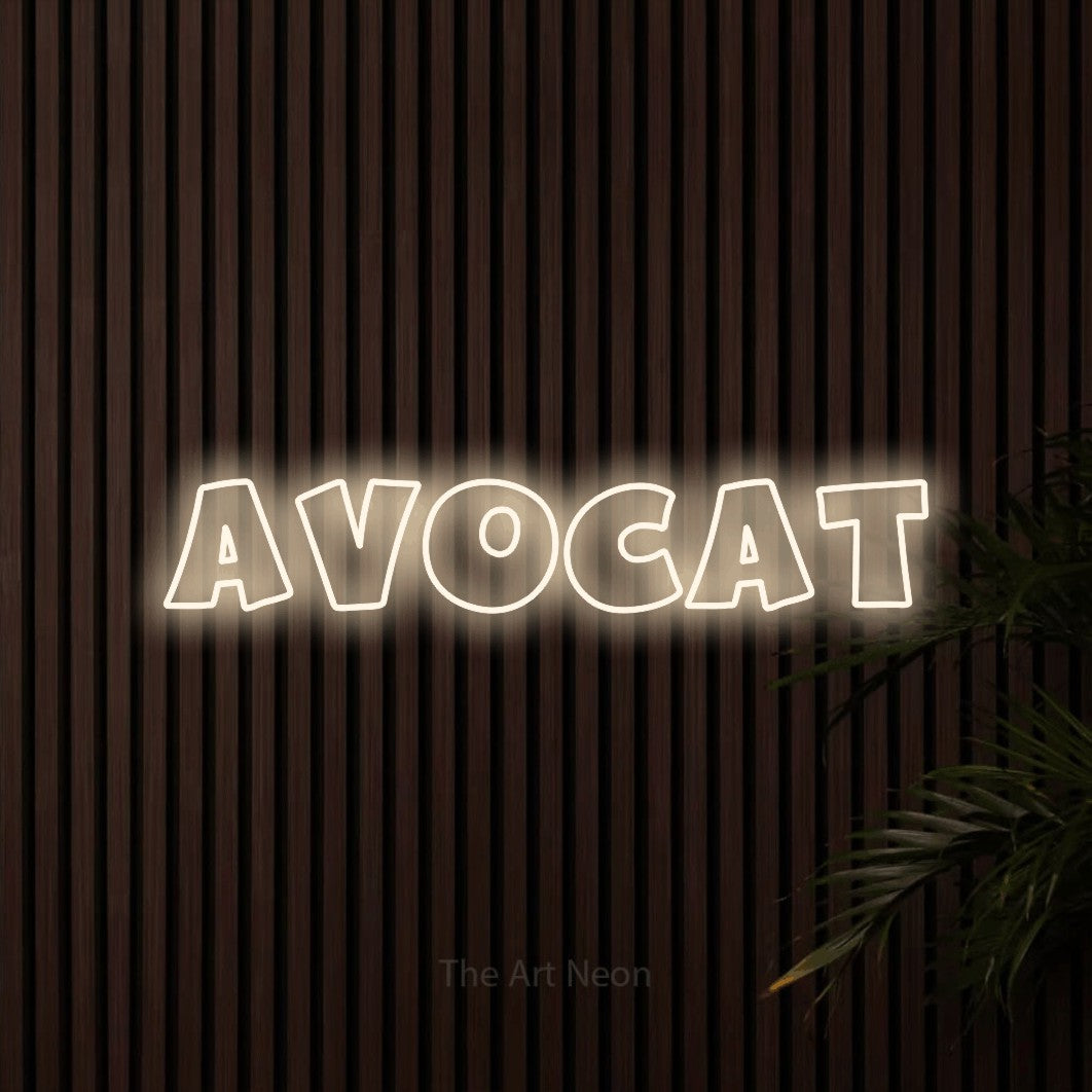 “Avocat” LED neon sign in warm white, with wide lettering with irregular outlines, shown against dark wooden wall slats.