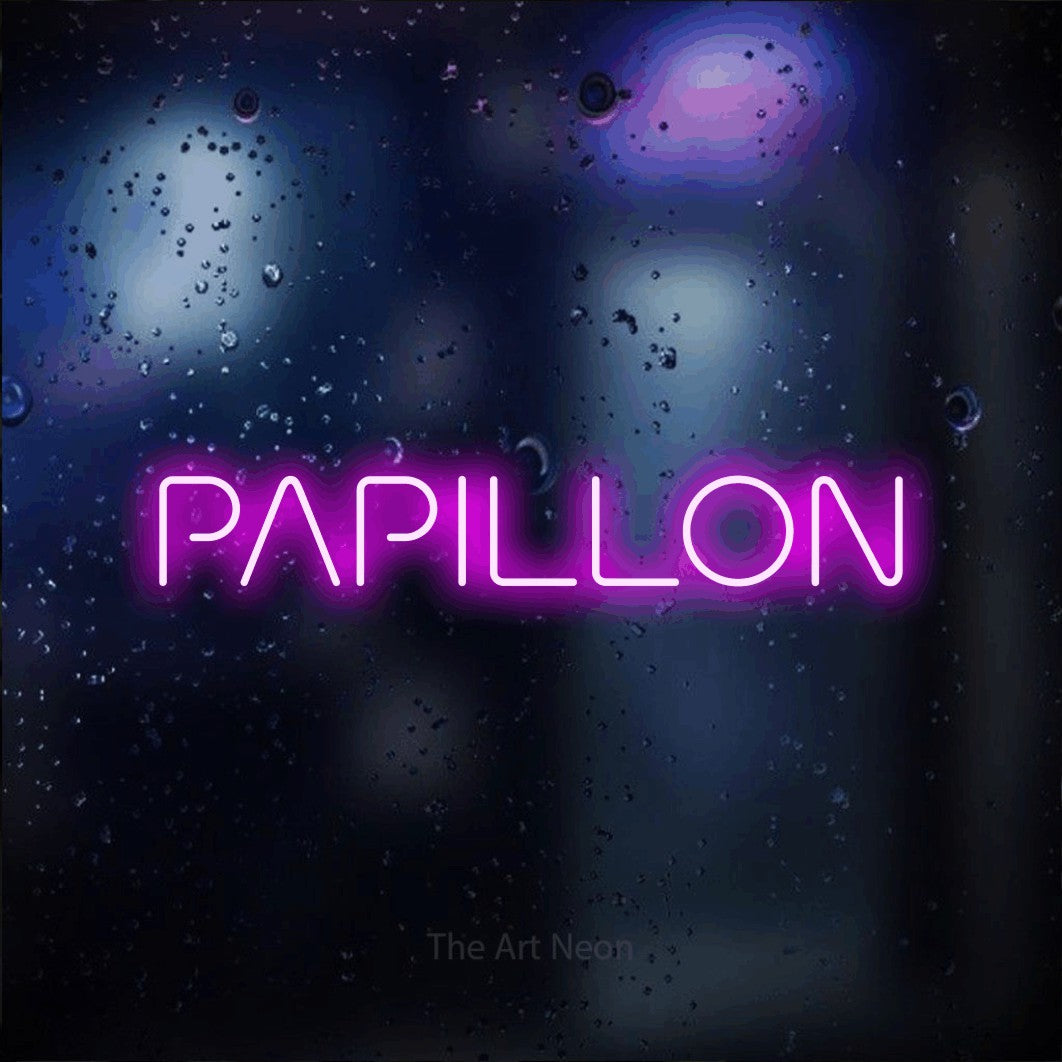 “Papillon” LED neon sign in pink, with stylised geometric lettering, shown against glass with blue and purple reflections.