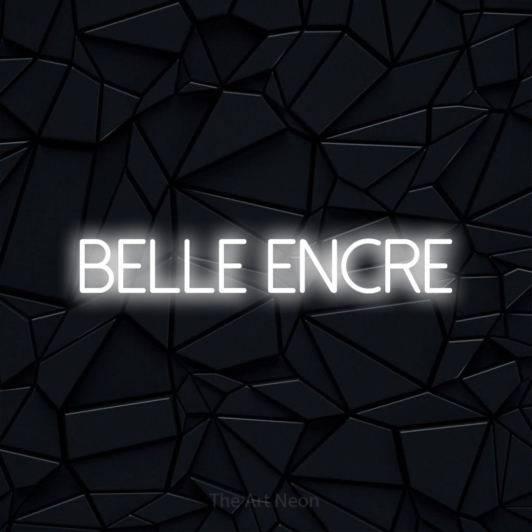 “Belle encre” LED neon sign in cool white, with thin sans-serif lettering, shown against a black polygonal surface.