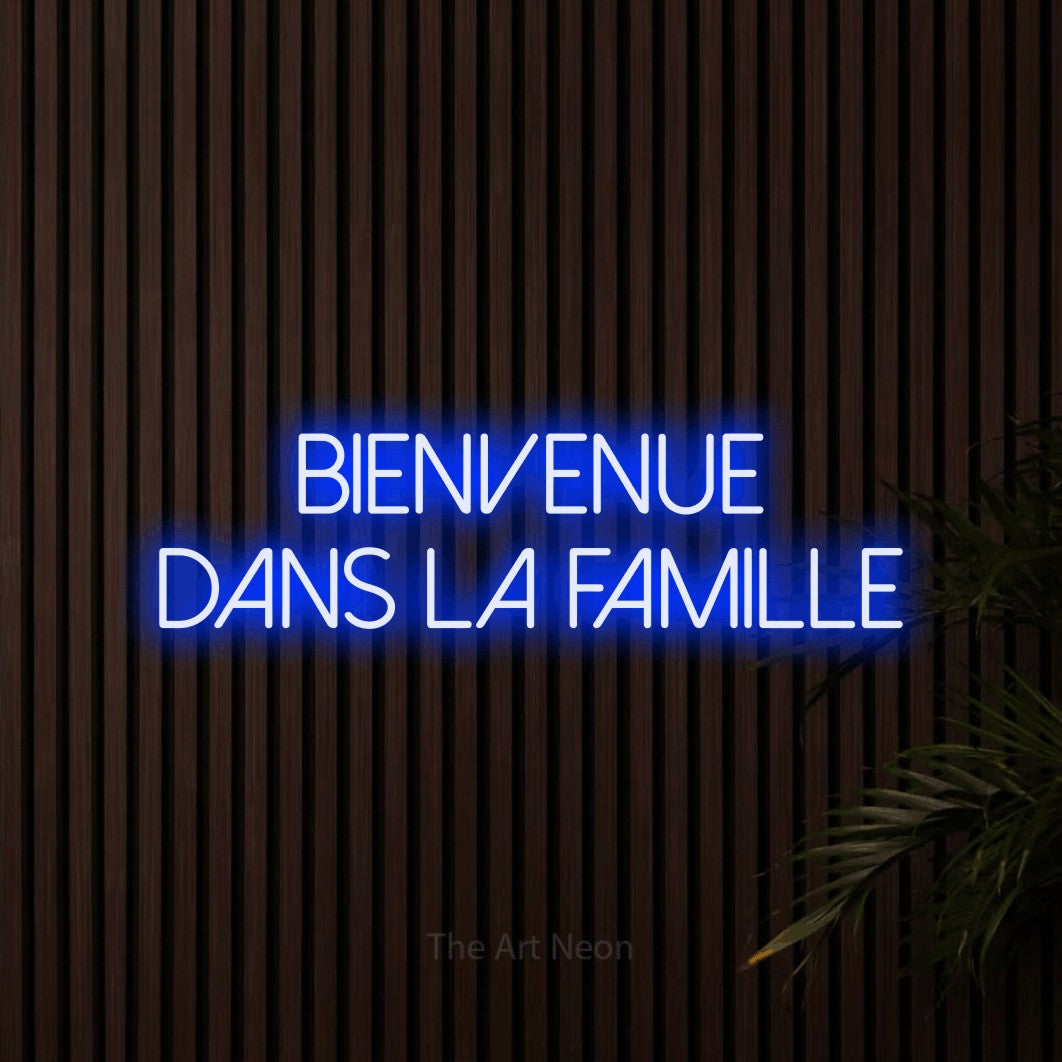 Lettrage en néon LED « Bienvenue dans la famille » sur deux lignes en bleu, en lettres fines sans empattement, présenté sur un mur de lattes en bois foncé, pour une fête prénatale.