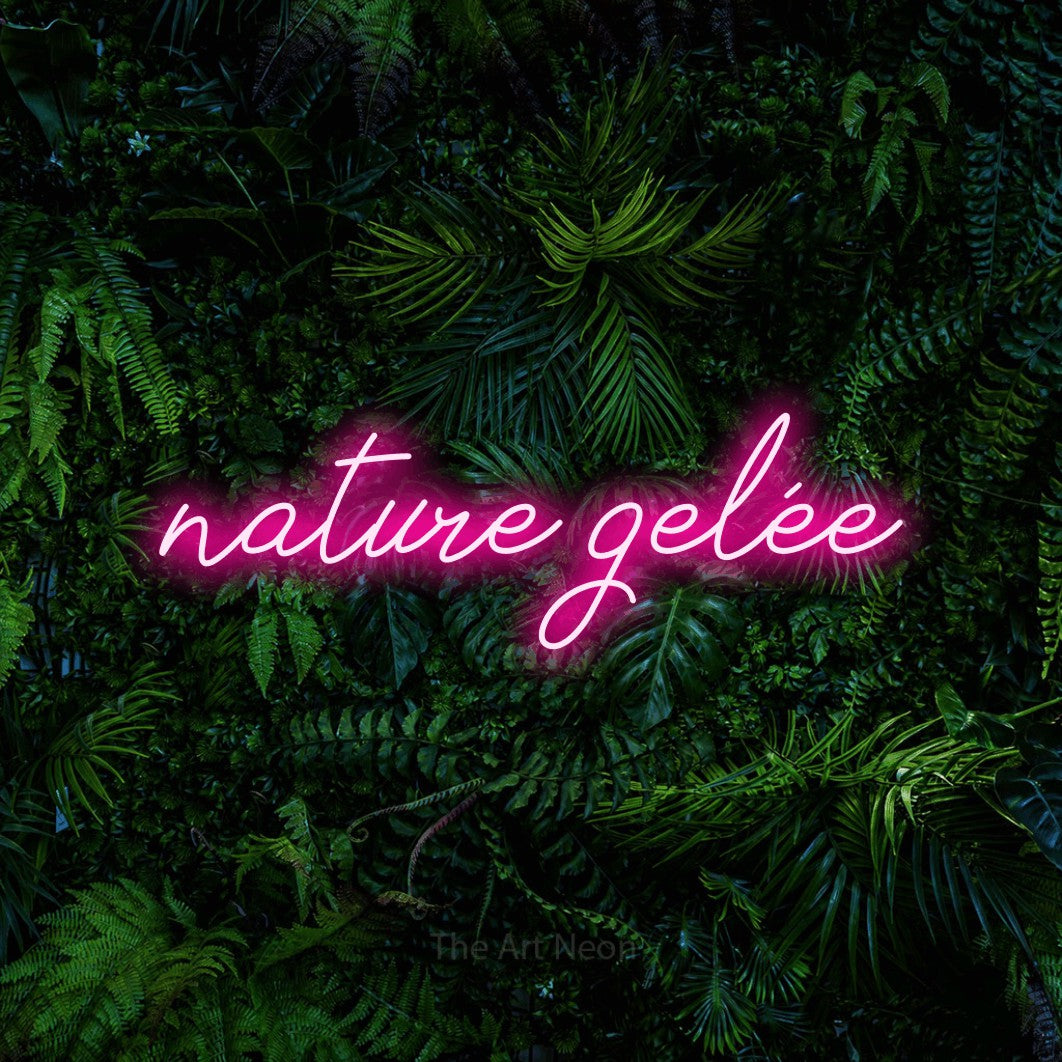 “Nature gelée” LED neon sign in hot pink, with cursive lettering, shown against dense tropical foliage.