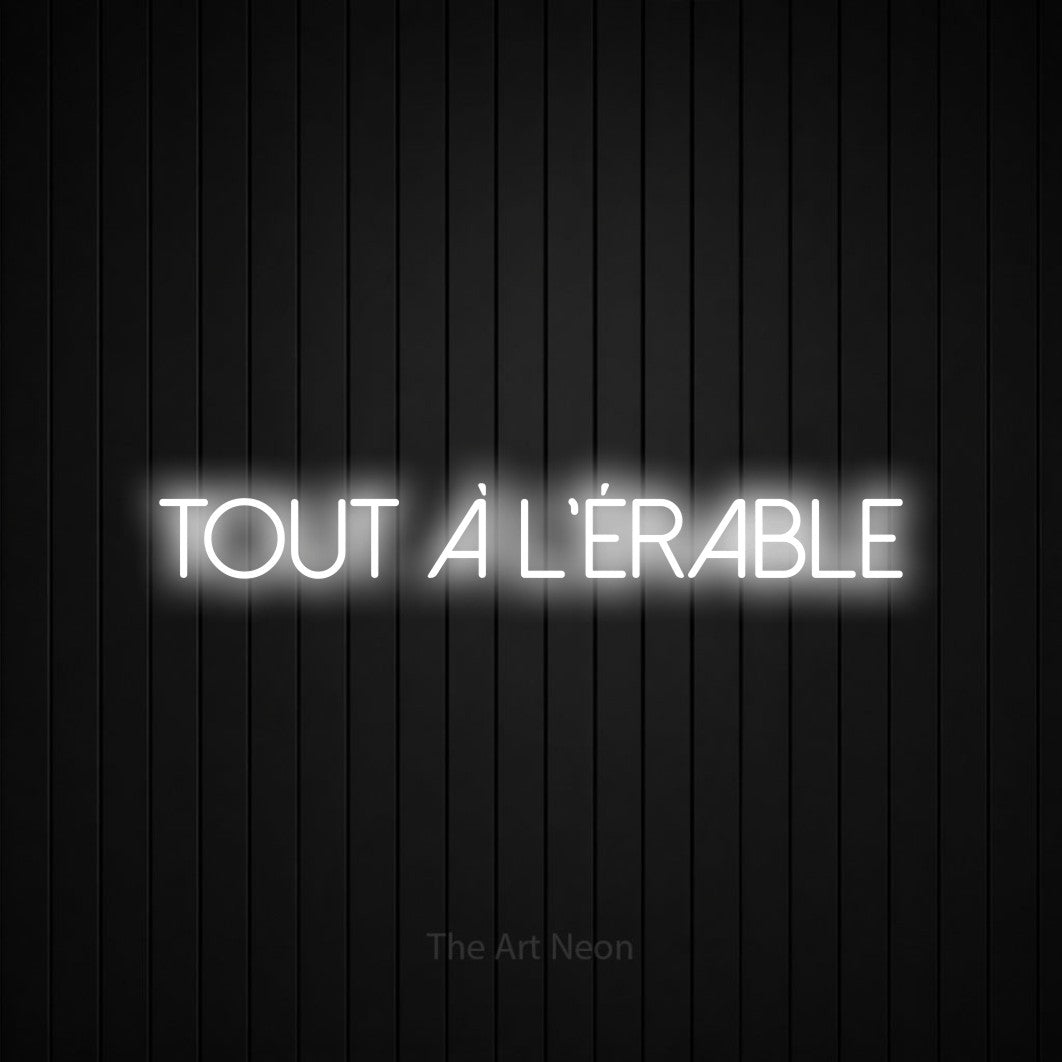 “Tout à l'érable” LED neon sign in cool white, with thin sans-serif lettering, shown against black vertical wall slats.