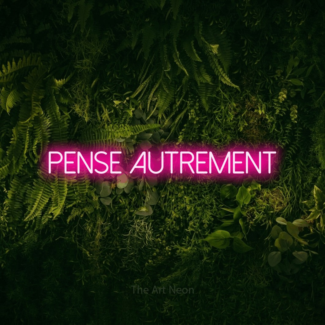 “Pense autrement” LED neon sign in hot pink, with thin sans-serif lettering, shown against a dark moss and forest backdrop.