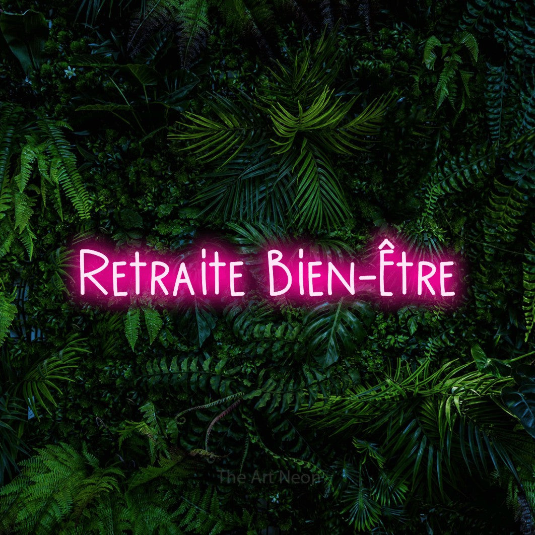 “Retraite bien-être” LED neon sign in hot pink, with narrow hand-drawn lettering, shown against dense tropical foliage.