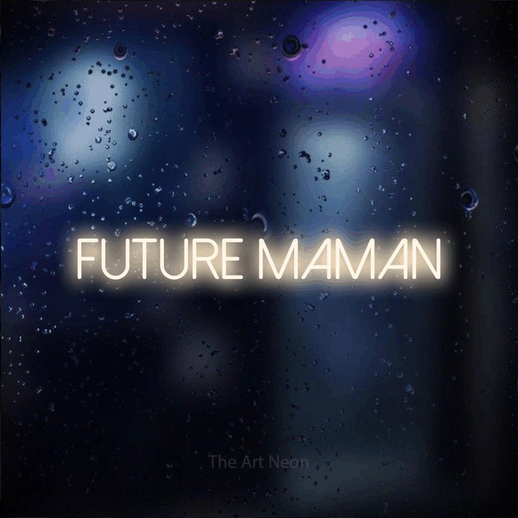 “Future maman” LED neon sign in warm white, with thin sans-serif lettering, shown against glass with blue and purple reflections.