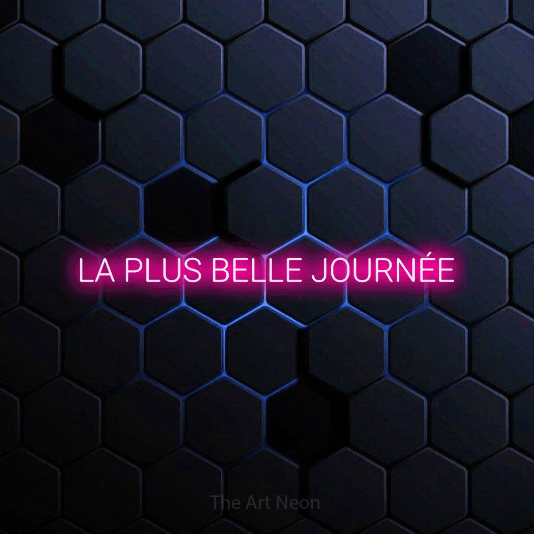 Néon LED « La plus belle journée » en rose vif, en lettres sans empattement arrondies, mis en scène sur un motif alvéolé bleu foncé, pour une fête.