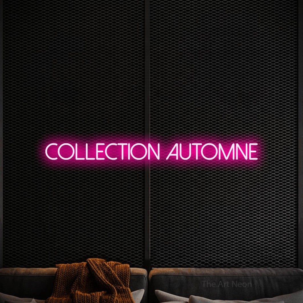 “Collection automne” LED neon sign in hot pink, with thin sans-serif lettering, shown against a modern dark-toned seating area.