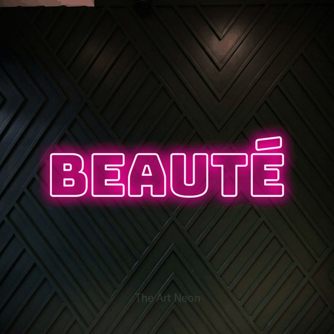 Aperçu d’une enseigne néon LED « Beauté » en rose vif, en typographie contour épaisse, photographiée sur un mur en bois noir à motif chevron, pour un salon de beauté.