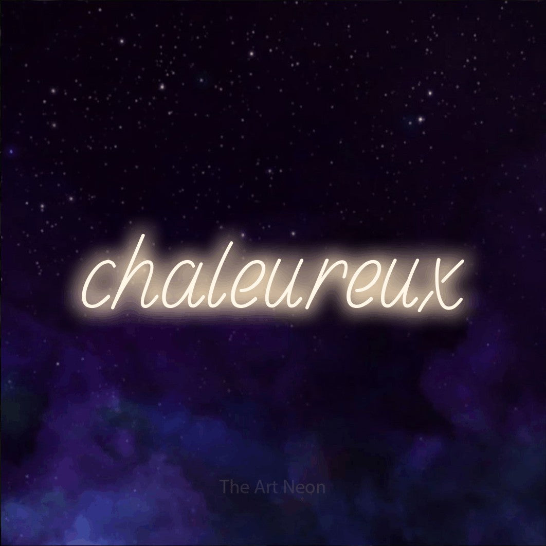 “Chaleureux” LED neon sign in warm white, with slanted handwritten lettering, shown against a purple galaxy backdrop.