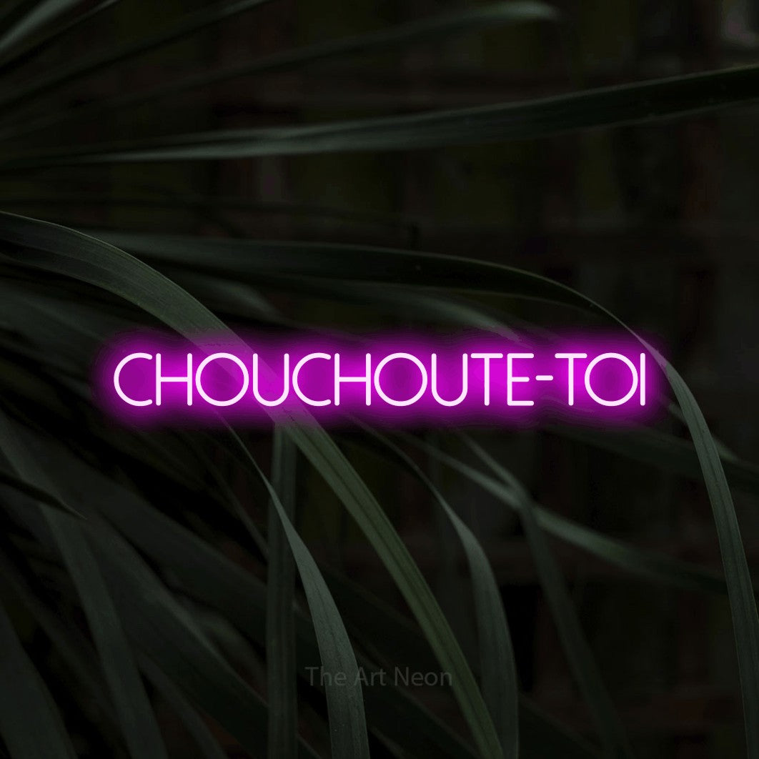 Néon LED « Chouchoute-toi » en rose, en lettres fines sans empattement, mis en scène sur un feuillage sombre en gros plan, pour un salon de beauté.