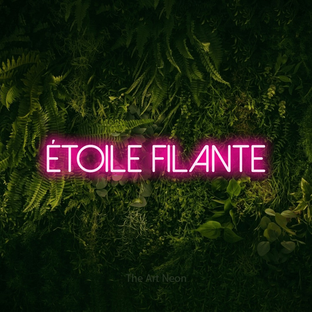 “Étoile filante” LED neon sign in hot pink, with thin sans-serif lettering, shown against a dark moss and forest backdrop.
