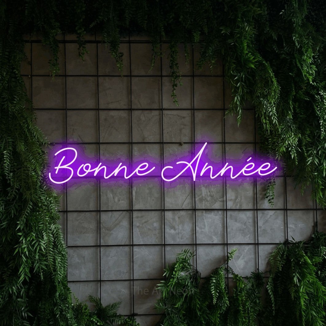 “Bonne année” LED neon sign in purple, with cursive lettering, shown against an ivy-covered concrete grid.