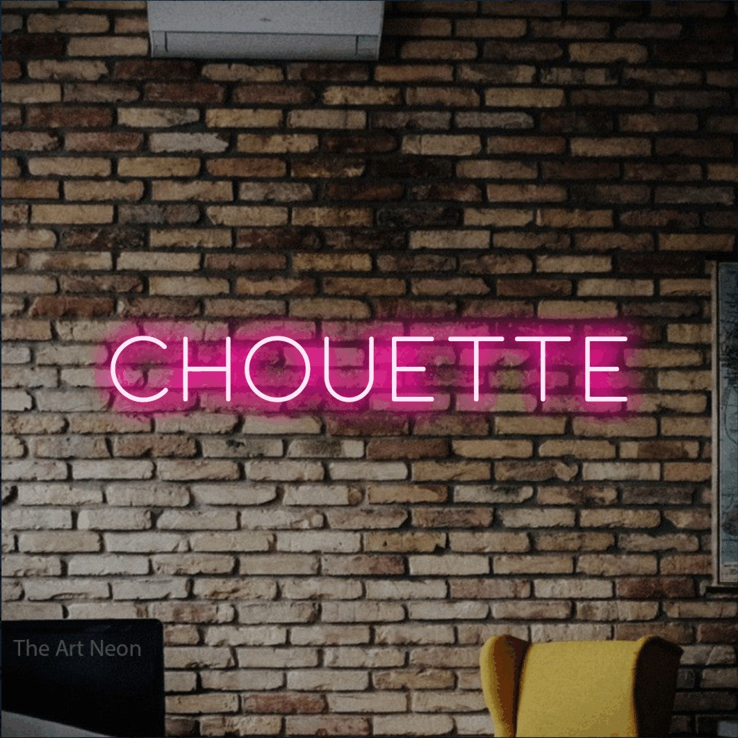 Lettrage en néon LED « Chouette » en rose vif, en lettres fines et espacées, présenté sur un mur de briques aux tons chauds, pour un décor inspiré de la nature.