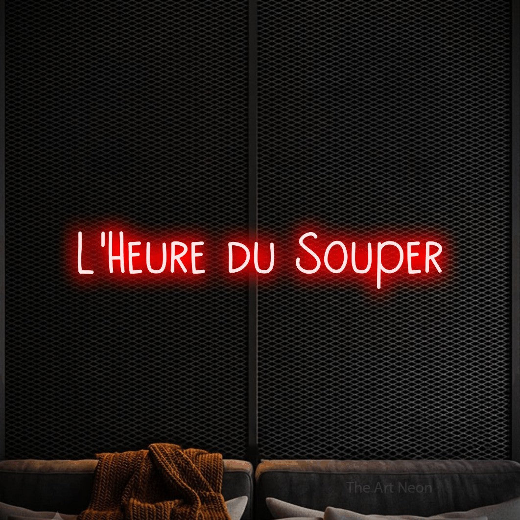 “L'heure du souper” LED neon sign in red, with narrow hand-drawn lettering, shown against a modern dark-toned seating area.