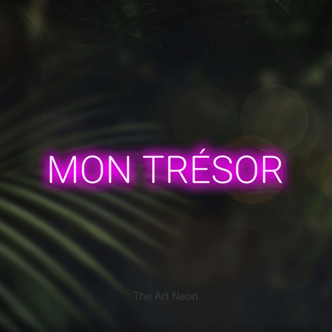 Aperçu d’une enseigne néon LED « Mon trésor » en rose, en lettres sans empattement arrondies, photographiée sur un fond flou de palmiers et de lumières bokeh, pour un décor romantique.