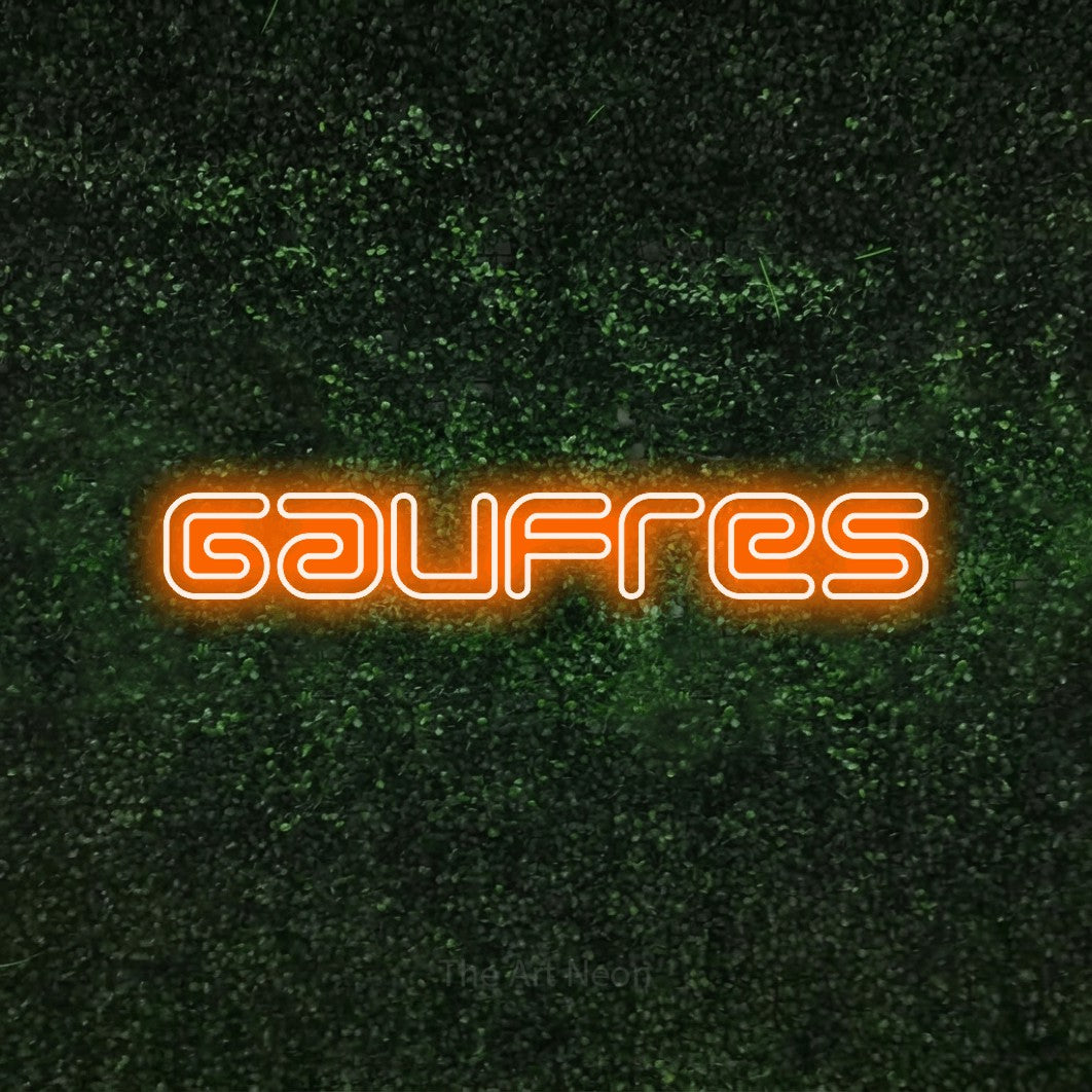 “Gaufres” LED neon sign in orange, with futuristic double-line lettering, shown against a textured green hedge.