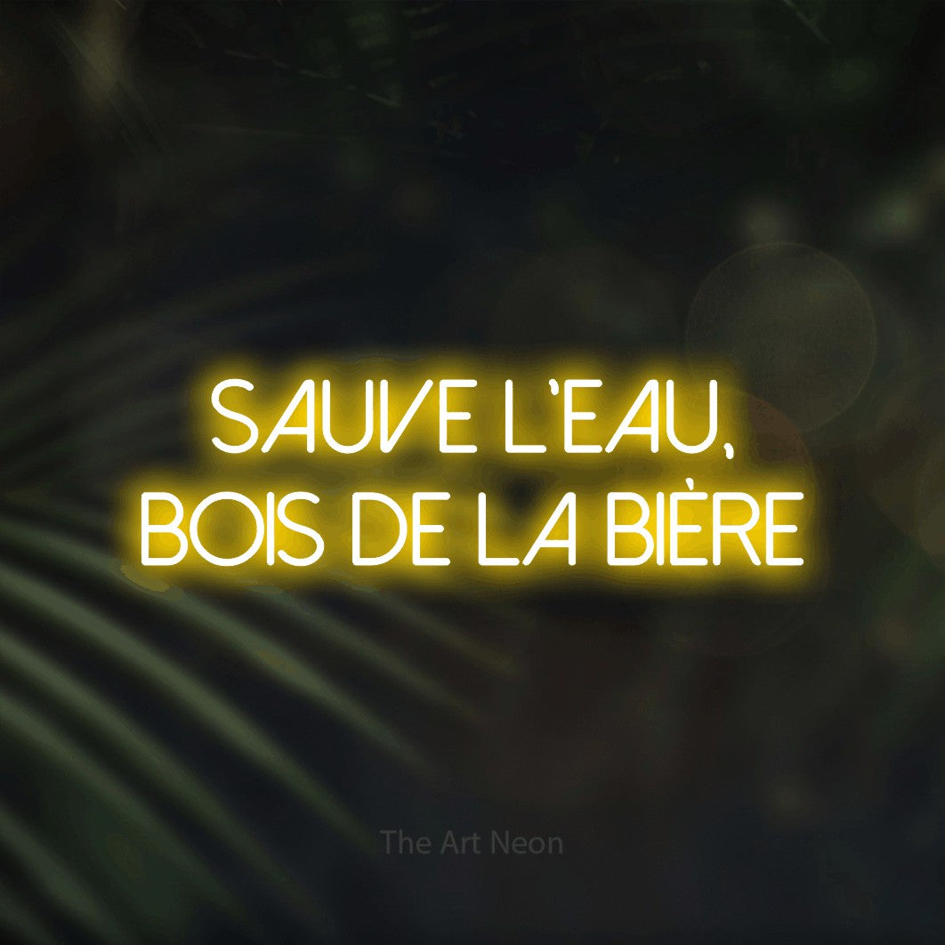 “Sauve l'eau, bois de la bière” LED neon sign in yellow, with thin sans-serif lettering across 2 lines, shown against a blurred palm and bokeh-light backdrop.