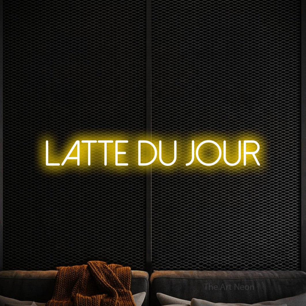 “Latte du jour” LED neon sign in yellow, with thin sans-serif lettering, shown against a modern dark-toned seating area.