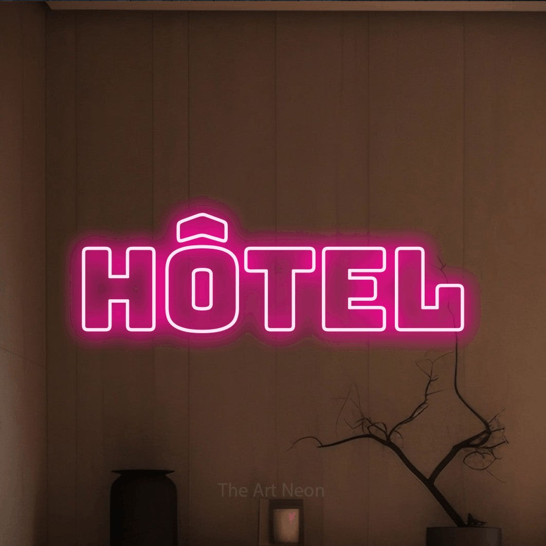 “Hôtel” LED neon sign in hot pink, with bold outline lettering, shown against a simple earth-toned interior.