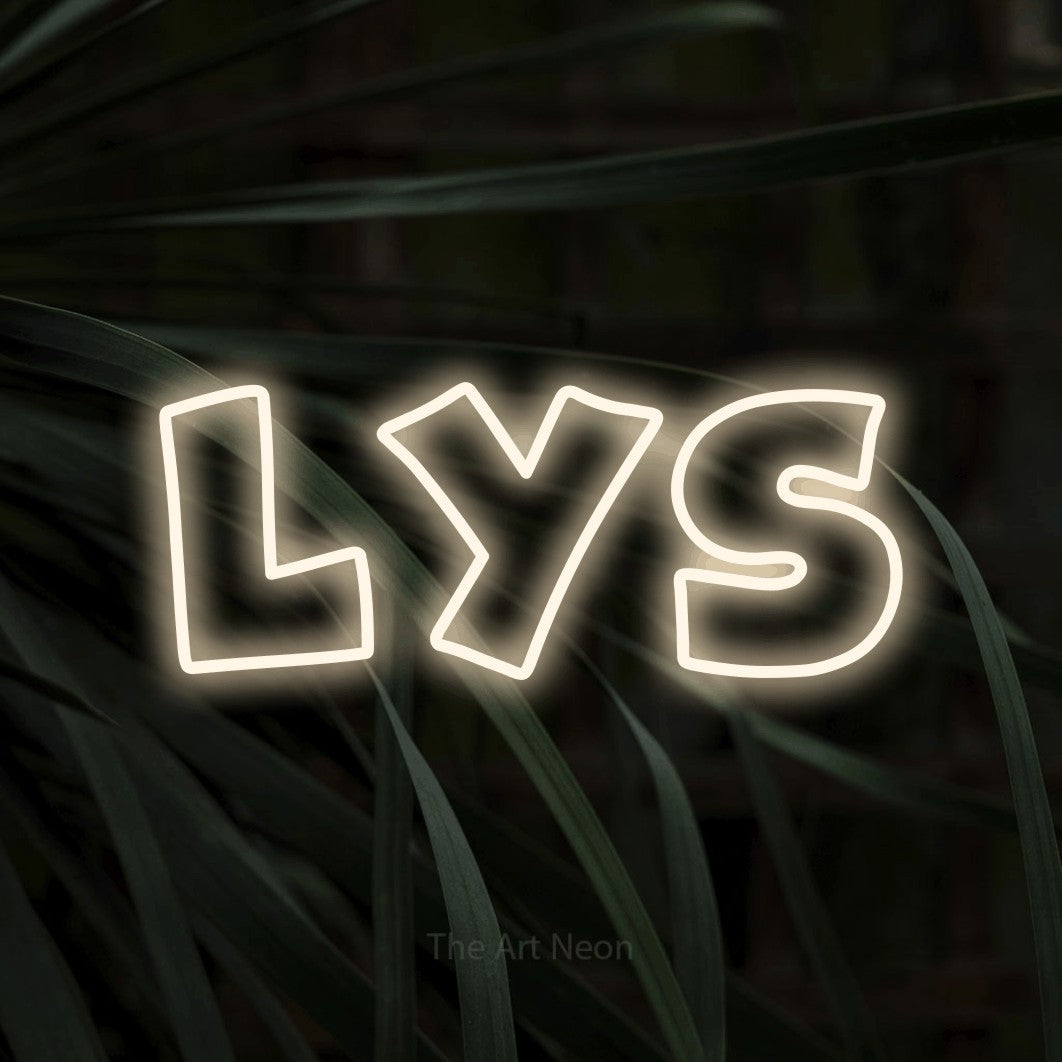 “Lys” LED neon sign in warm white, with wide lettering with irregular outlines, shown against a close-up of dark foliage.