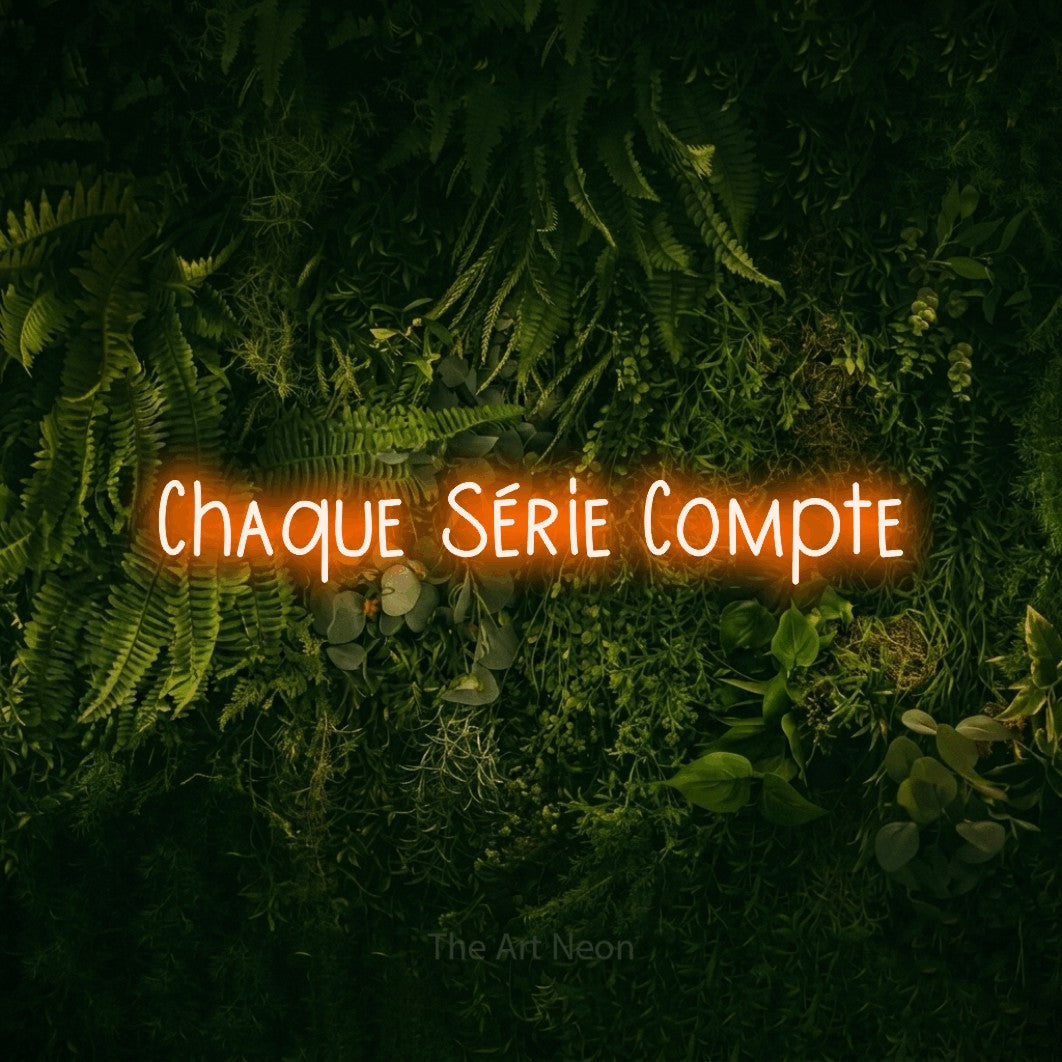 “Chaque série compte” LED neon sign in orange, with narrow hand-drawn lettering, shown against a dark moss and forest backdrop.