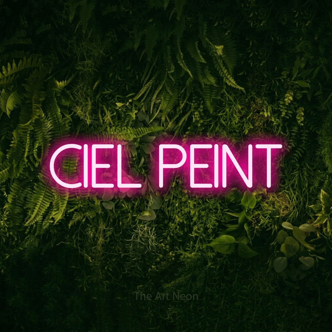 “Ciel peint” LED neon sign in hot pink, with thin sans-serif lettering, shown against a dark moss and forest backdrop.