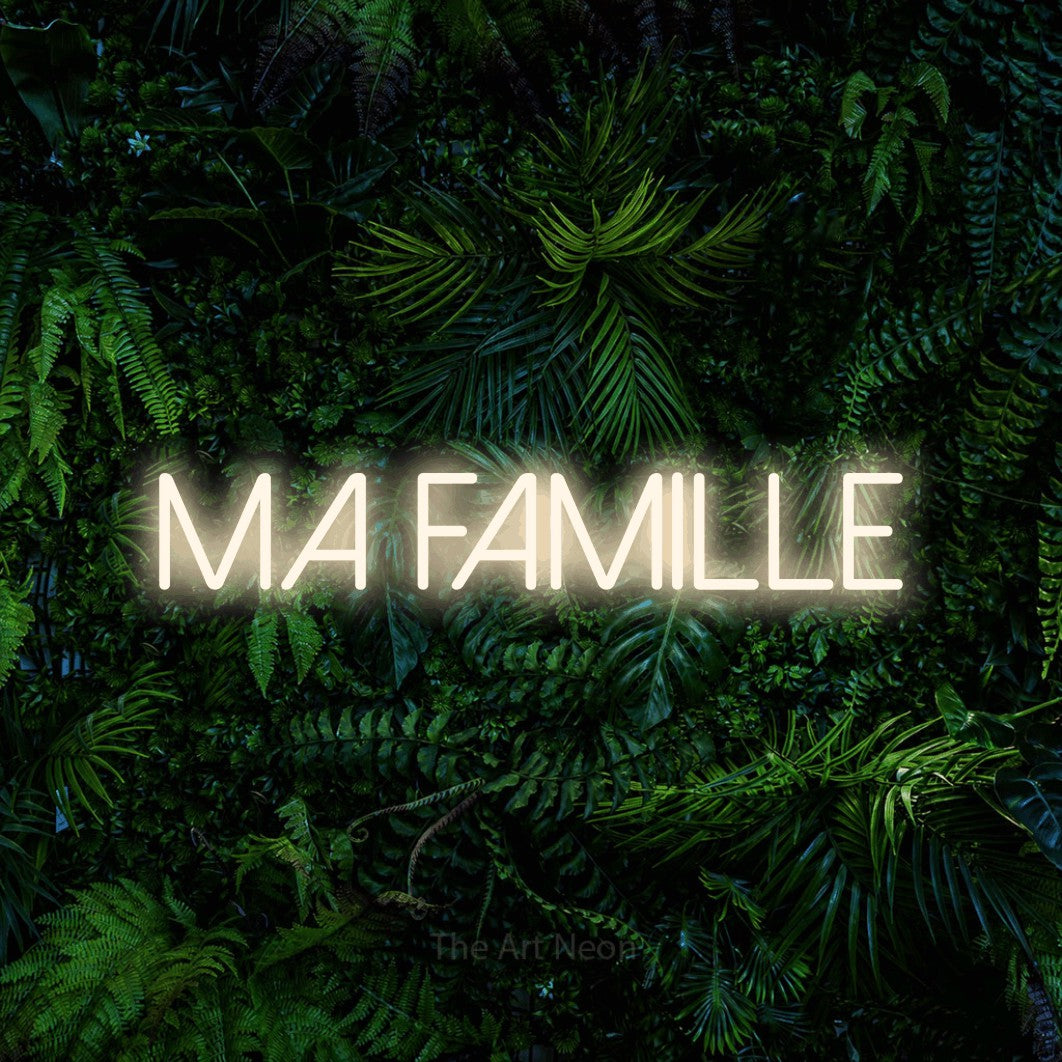 “Ma famille” LED neon sign in warm white, with thin sans-serif lettering, shown against dense tropical foliage.