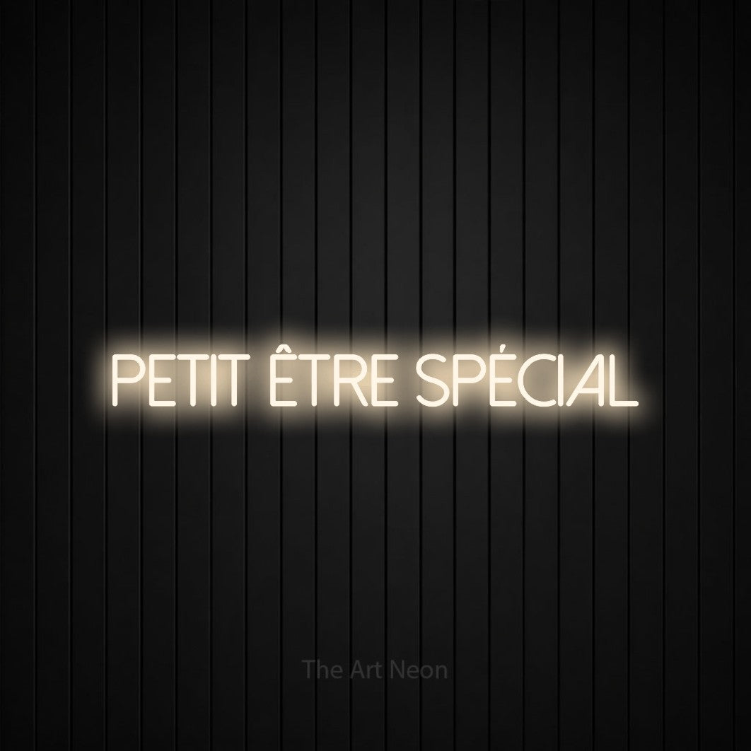 Enseigne néon LED « Petit être spécial » en blanc chaud, en lettres fines sans empattement, présentée sur un mur de lattes verticales noires, pour une fête prénatale.