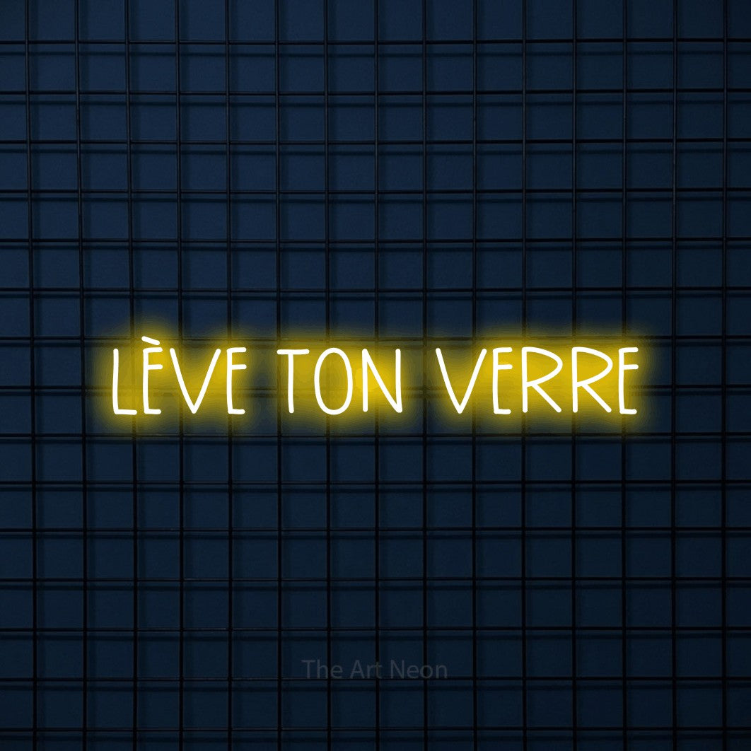 Enseigne néon LED « Lève ton verre » en jaune, en lettres étroites dessinées à la main, présentée sur une grille bleu foncé, pour une fête.