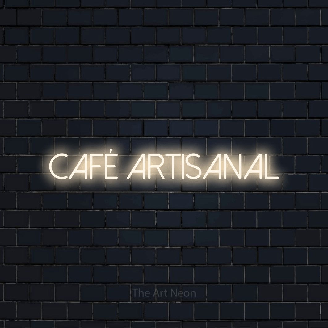 Décoration murale en néon LED « Café artisanal » en blanc chaud, en lettres fines sans empattement, installée sur un mur de briques bleu marine foncé, pour un café.