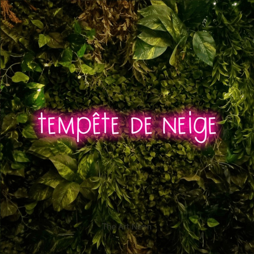 Lettrage en néon LED « Tempête de neige » en rose vif, en lettres étroites dessinées à la main, présenté sur un feuillage vert et jaune vif, pour un décor canadien.