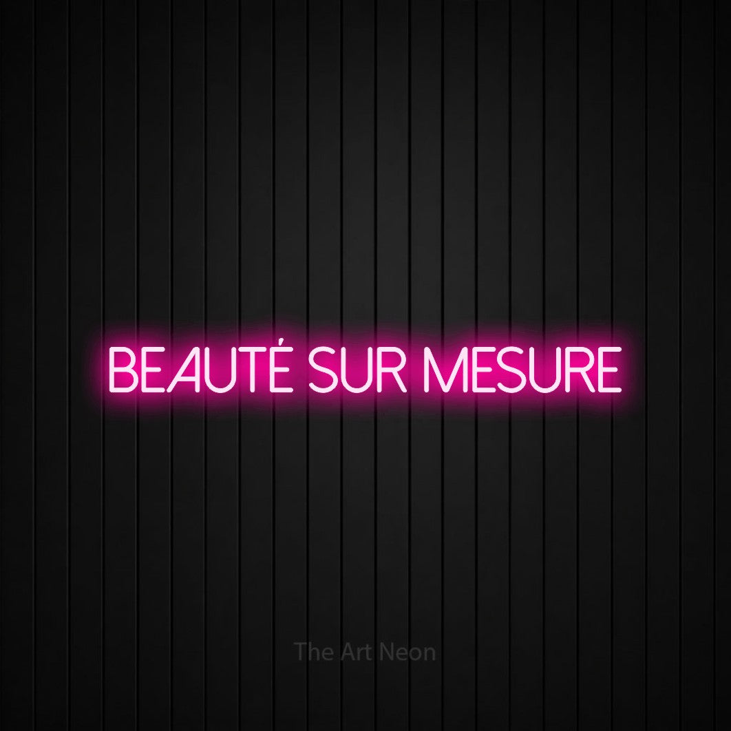 “Beauté sur mesure” LED neon sign in hot pink, with thin sans-serif lettering, shown against black vertical wall slats.