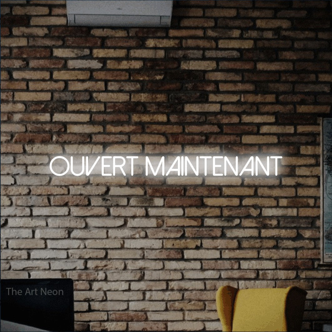 “Ouvert maintenant” LED neon sign in cool white, with thin sans-serif lettering, shown against warm-toned brickwork.