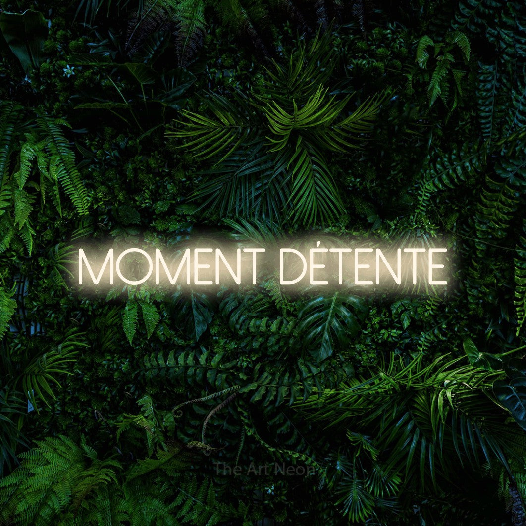 Néon LED « Moment détente » en blanc chaud, en lettres fines sans empattement, mis en scène devant un feuillage tropical dense, pour un salon de beauté.