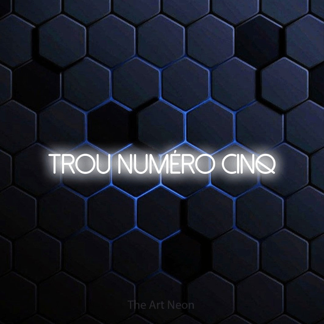“Trou numéro cinq” LED neon sign in cool white, with thin sans-serif lettering, shown against a dark blue honeycomb pattern.