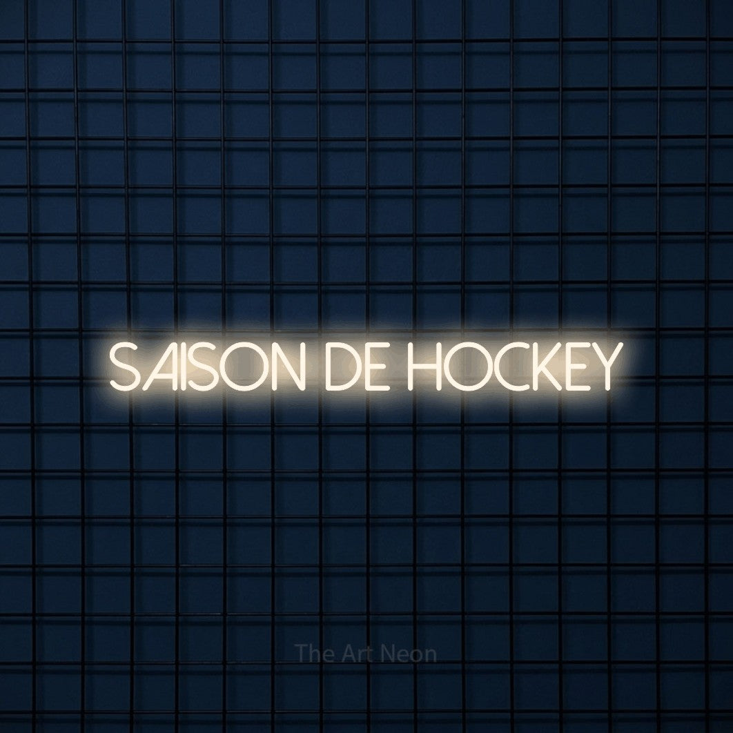 “Saison de hockey” LED neon sign in warm white, with thin sans-serif lettering, shown against a dark blue grid.