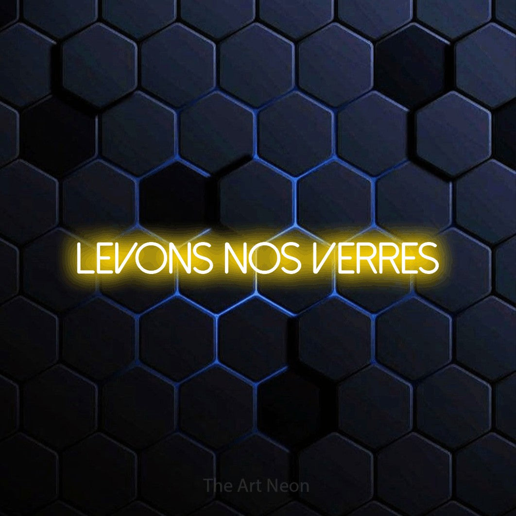 “Levons nos verres” LED neon sign in yellow, with thin sans-serif lettering, shown against a dark blue honeycomb pattern.