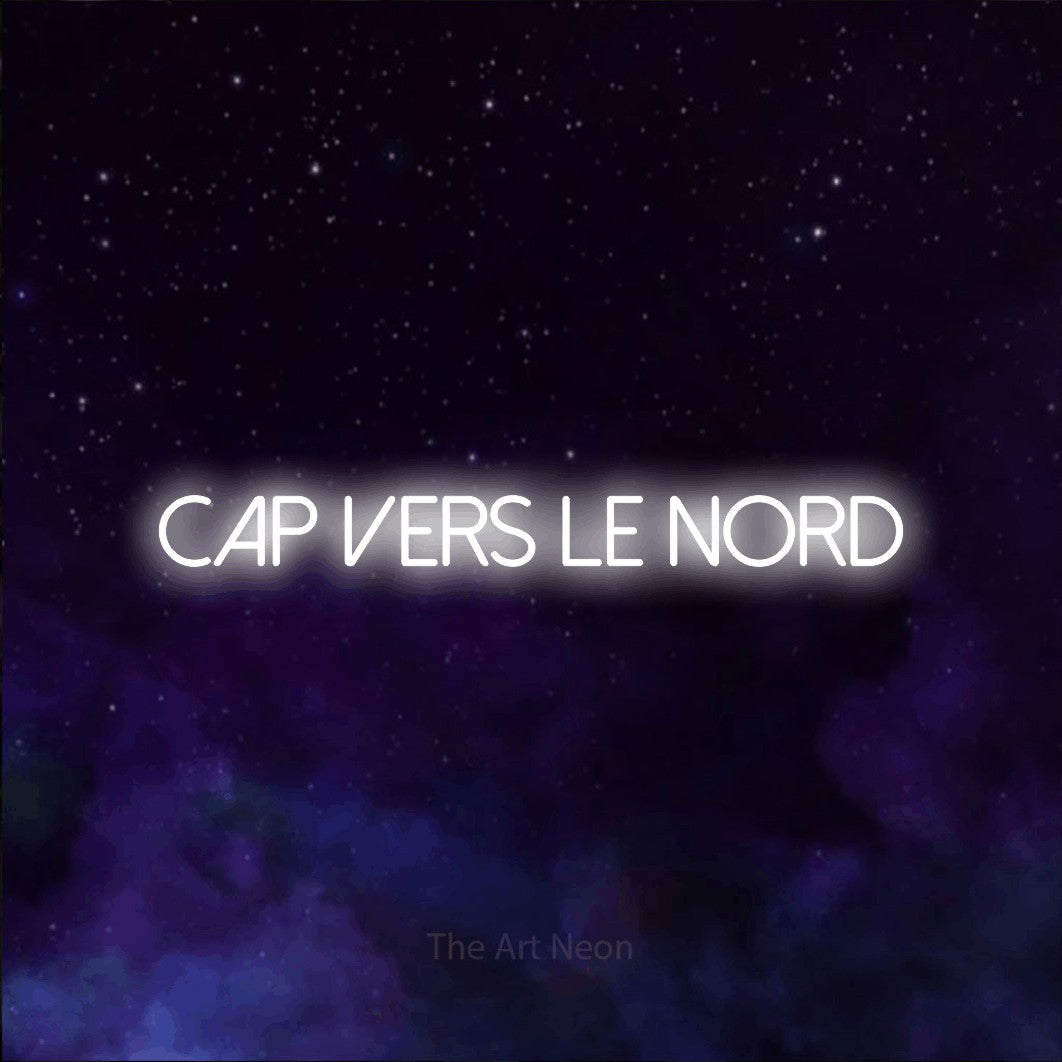 “Cap vers le nord” LED neon sign in cool white, with thin sans-serif lettering, shown against a purple galaxy backdrop.