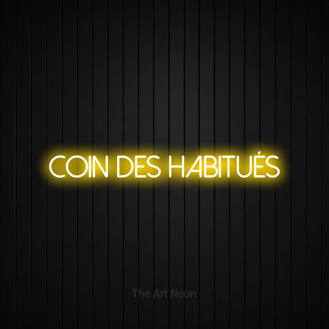 “Coin des habitués” LED neon sign in yellow, with thin sans-serif lettering, shown against black vertical wall slats.